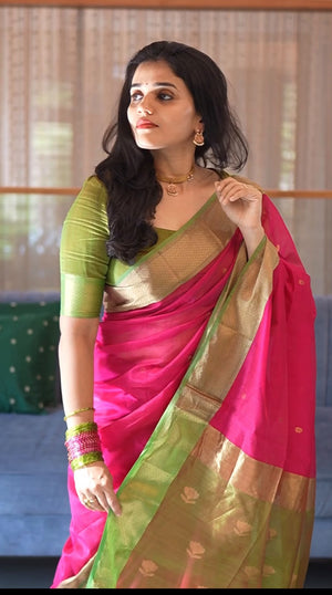 Model wearing a fuchsia-pink Maheswari handwoven silk-cotton saree with an olive-green blouse and olive-green, gold-toned border and pallu