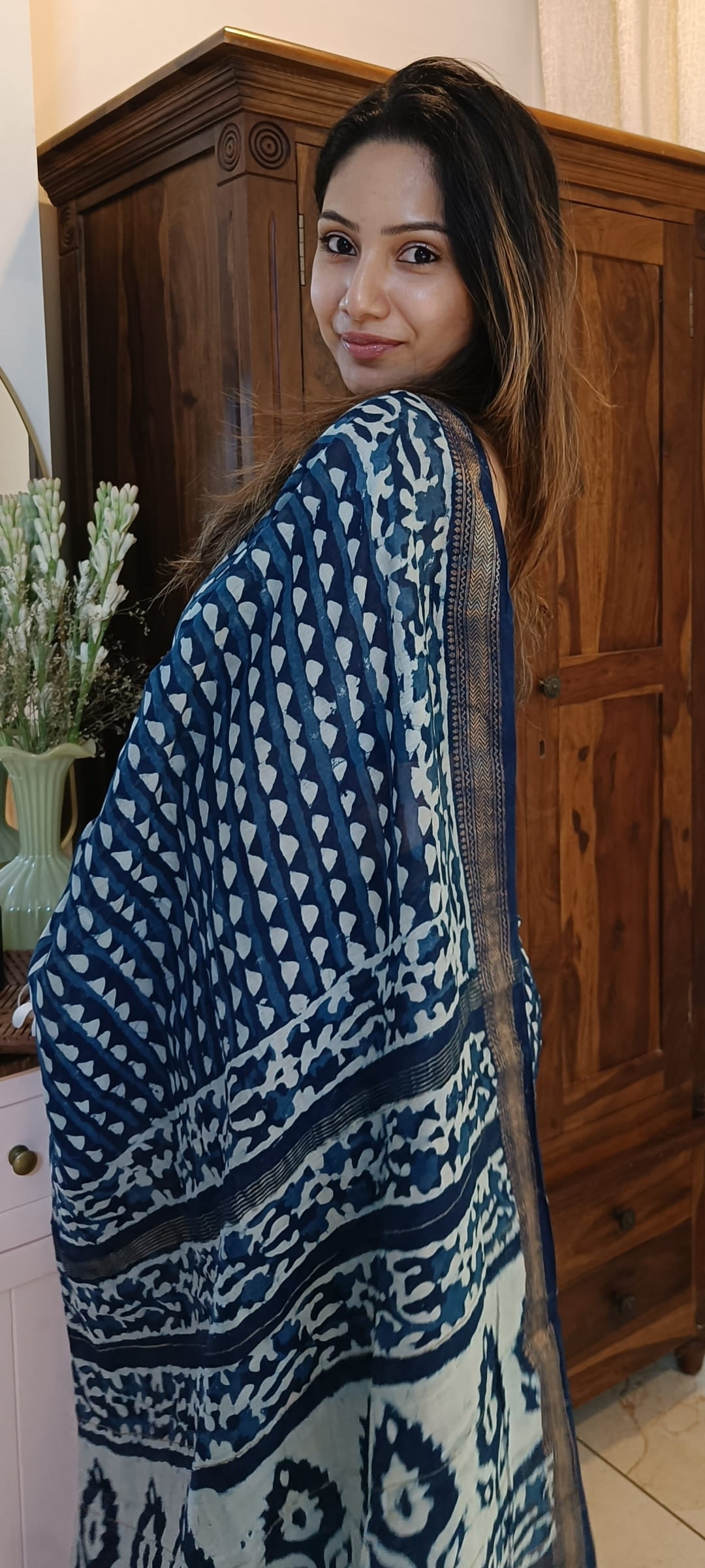 Model showing the indigo saree's ivory motifs, patterned pallu, and contrast border