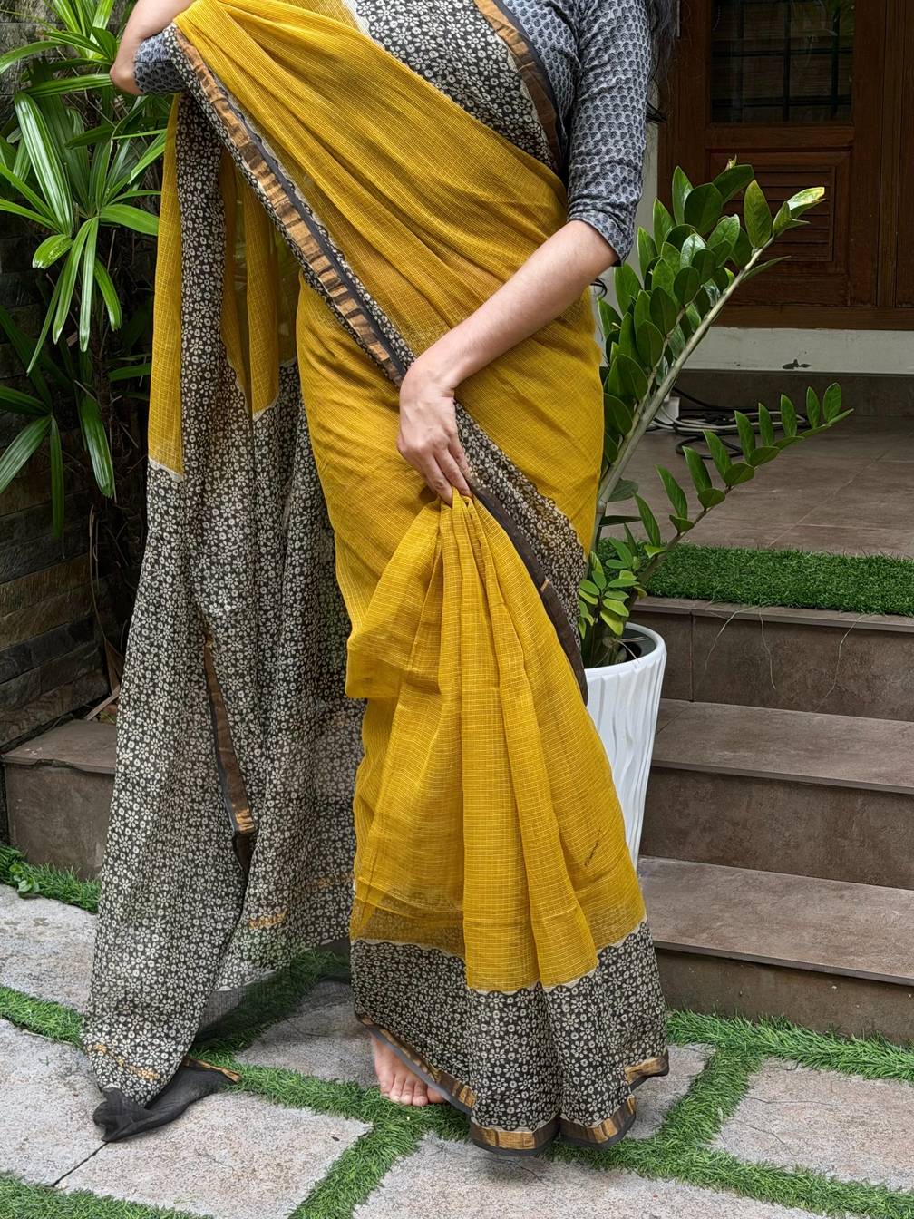 Aaranya Kota Doria saree showing mustard pleats and dark floral border