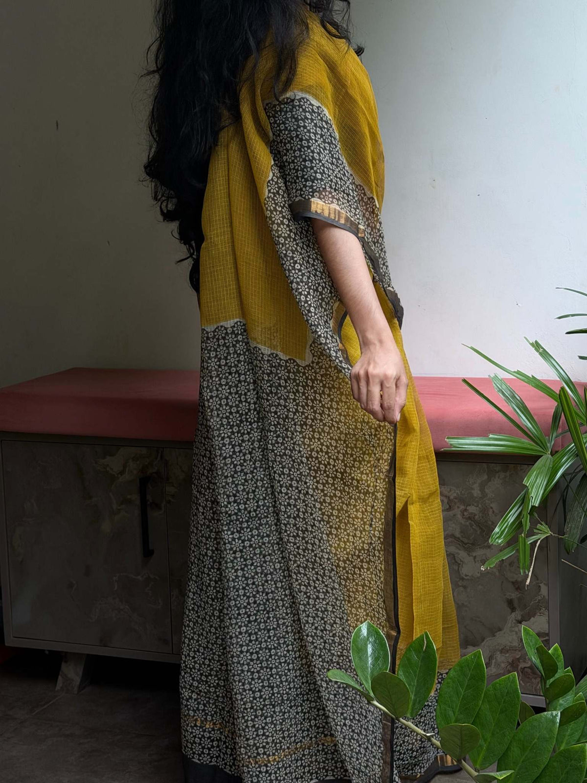 Seated view of Aaranya mustard Kota Doria saree with floral pallu