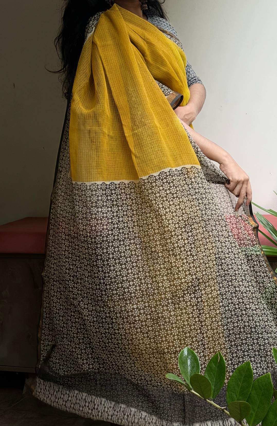 Aaranya mustard yellow Kota Doria saree with dark floral border, full-length outdoor view