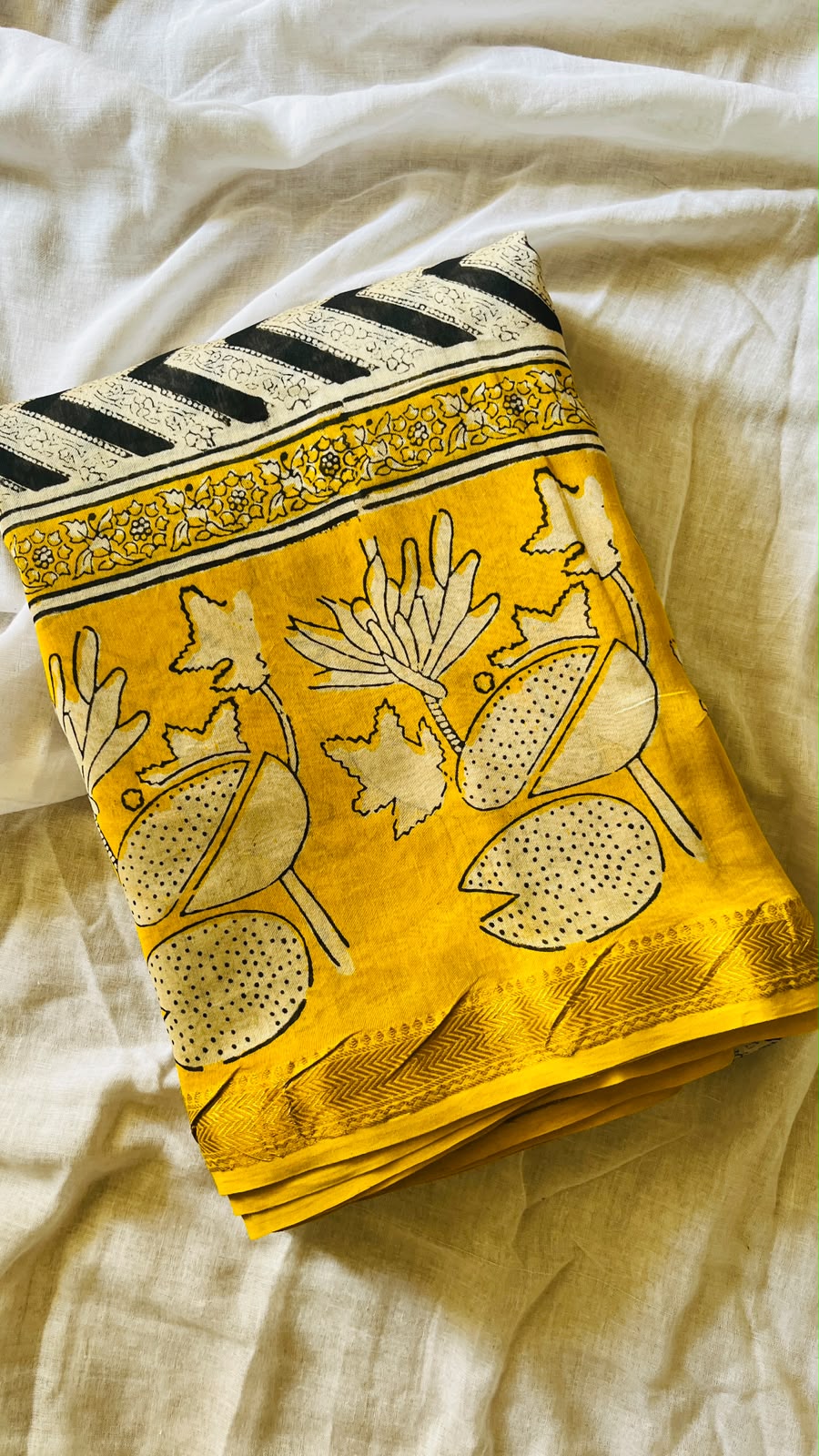 Folded haldi-yellow Maheswari handblocked silk cotton saree showing the patterned pallu and border