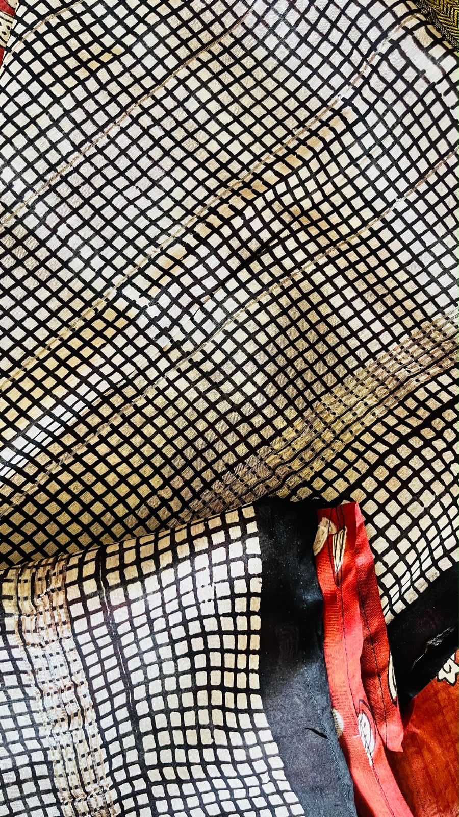 Folded Agnika Maheswari handblocked saree with red paisley pallu, black grid border, and gold-toned accents