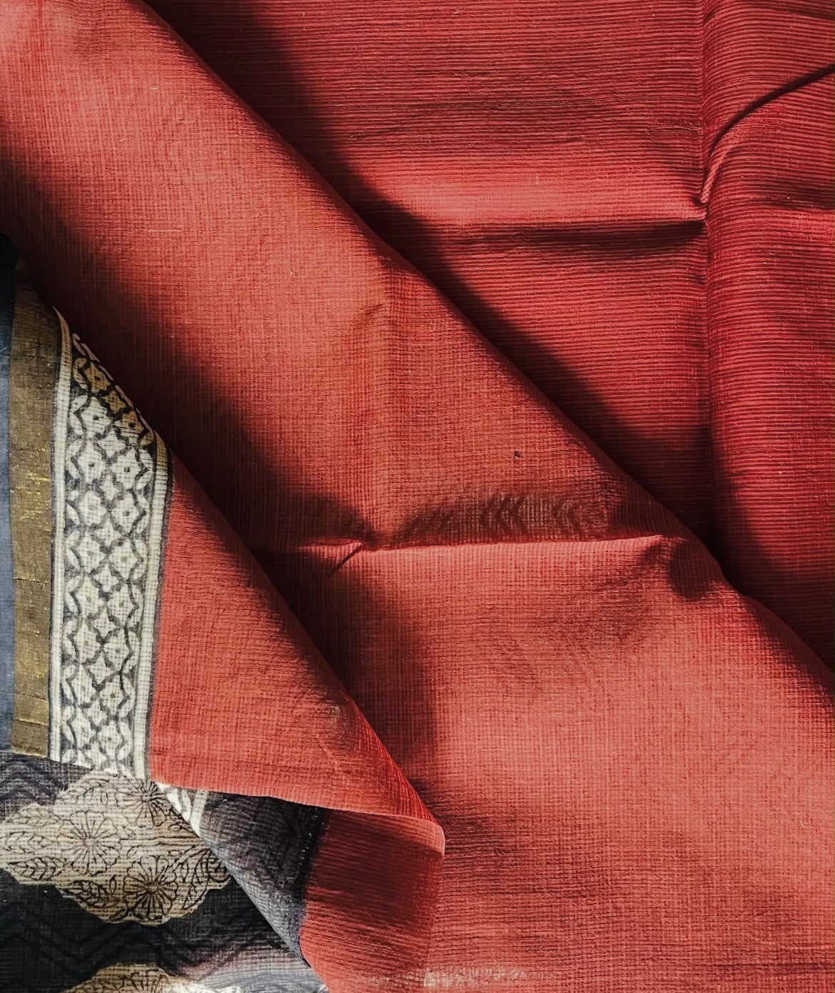 Close-up of Ruhani saree's textured brick red body and contrasting patterned border